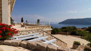 A stone staircase leading to a terrace with a white railing, overlooking a body of water and hills. - Liladi Stone-Built Villa With Exclusive Pool. (Fiskardo)