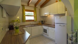 A kitchen with white cabinets, a wooden countertop, a built-in oven, and a refrigerator. - Promana -Villa Ricarda with private pool 850m to the sea between Moraira & Calpe (Benissa)