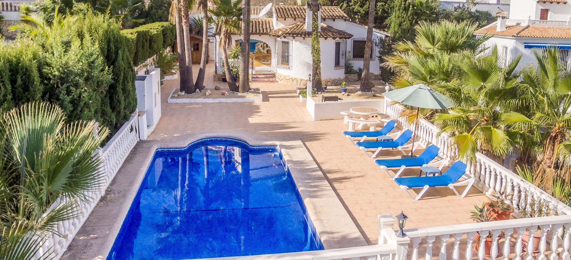 A pool area with a clear view of the surrounding buildings, palm trees, and a satellite dish.