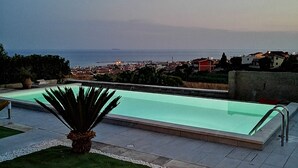 A swimming pool with a view of the sea and a cityscape in the background. - Villa Eleonora Home Holiday (Marina di Ragusa)