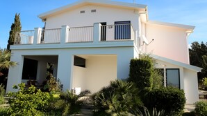 A modern two-story house with a balcony, a small attached garage, and a well-maintained garden. - Villa Eleonora Home Holiday (Marina di Ragusa)