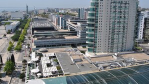 A high-rise building with a unique conical top, surrounded by modern architecture and a waterfront view.