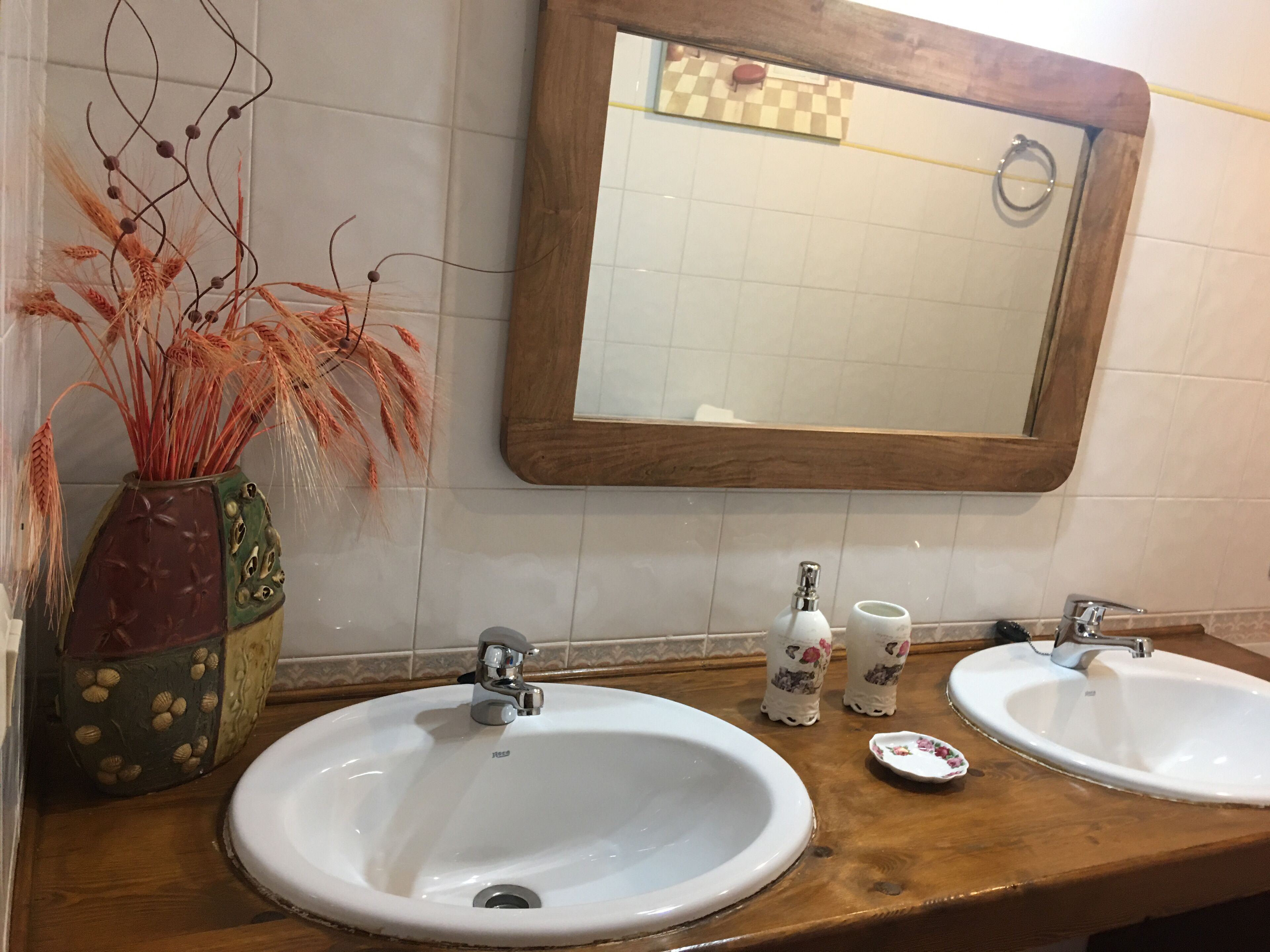 Un baño con dos lavamanos, un espejo y detalles decorativos.