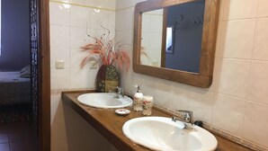 A bathroom with two sinks, a mirror, and a vase with dried plants. - ACCOMMODATION IN PEDRAZA - MERCHE 1 (Pedraza)
