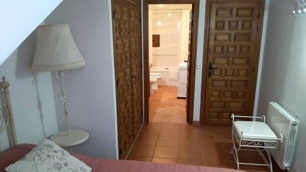 A bedroom with a bed, a bedside lamp, a radiator, and a wooden wardrobe. - ACCOMMODATION IN PEDRAZA - MERCHE 1 (Pedraza)