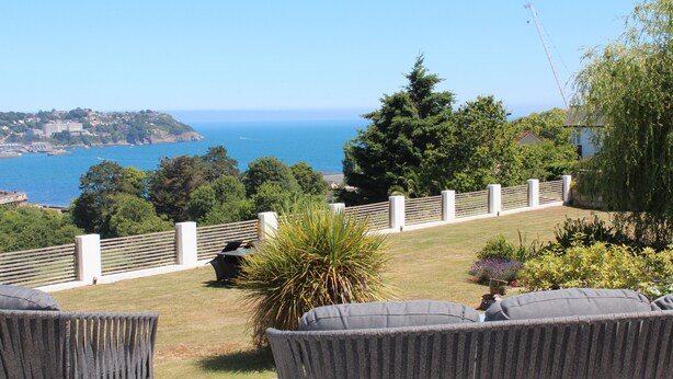 A patio with outdoor furniture, a view of the sea, and a landscaped garden. - Luxury Apartment - Sleeps 4 -  Spectacular Views with Private Pool and Hot Tub   (Torquay)