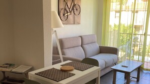 A living room with a sofa, a dining table with chairs, a lamp, and a wall-mounted bicycle artwork. - Luxury Apartment (Collioure)