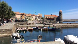 A harbor with boats, a stone tower, and colorful buildings. - Luxury Apartment (Collioure)