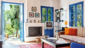 A living room with a fireplace, a television, and a sofa with cushions.