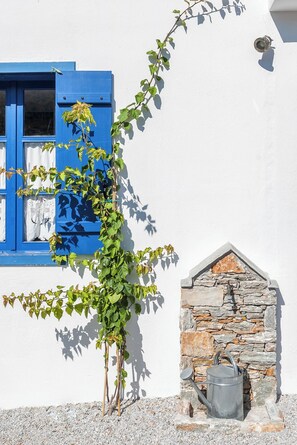 A white building with blue shutters and a stone wall.