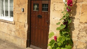 A stone building with a wooden door and a window to the left. - Wonderful Grade II Cotswold Stone Cottage in Perfect Location (Chipping Campden)