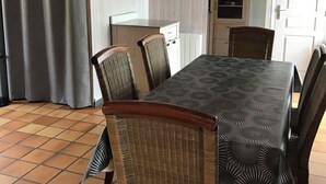 A dining area with a table and chairs, a kitchen area with cabinets and a microwave, and a door with a white frame.