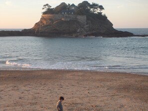 A beach with a rocky outcrop and a building on top. - House ST COULOMB, near beaches, La Grange de la Ville Huet (Saint-Coulomb)