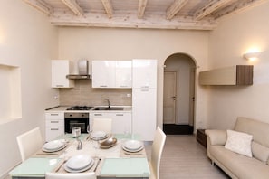 A compact kitchen with white cabinets, a stove, and a dining area with a table set for two.