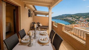 A balcony with a table set for dining, overlooking a coastal town. - Brigata House-Luxury 2 bed apartment with sea views, close to sea and shops,wifi (Castelsardo)