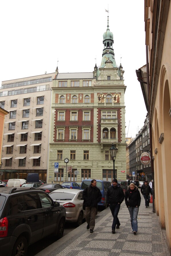 A street with parked cars and pedestrians walking.