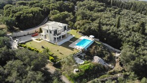 An aerial view of a modern two-story house with a swimming pool, surrounded by dense forest. - Rent Villa In Corfu, Private Pool, Luxurious, Gorgeous Views, In House Catering (Klimatia Karousades)