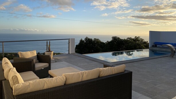 Une terrasse sur le toit avec une piscine, des meubles en osier et une vue sur l’océan.