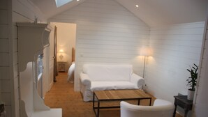 Een knus ingerichte kamer met witte meubels, een houten vloer en een schuine kap.
