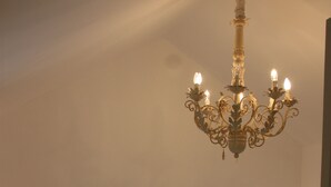 Een slaapkamer met een groot bed, twee nachtkastjes met lampen, een houten hoofdbord en een kroonluchter.