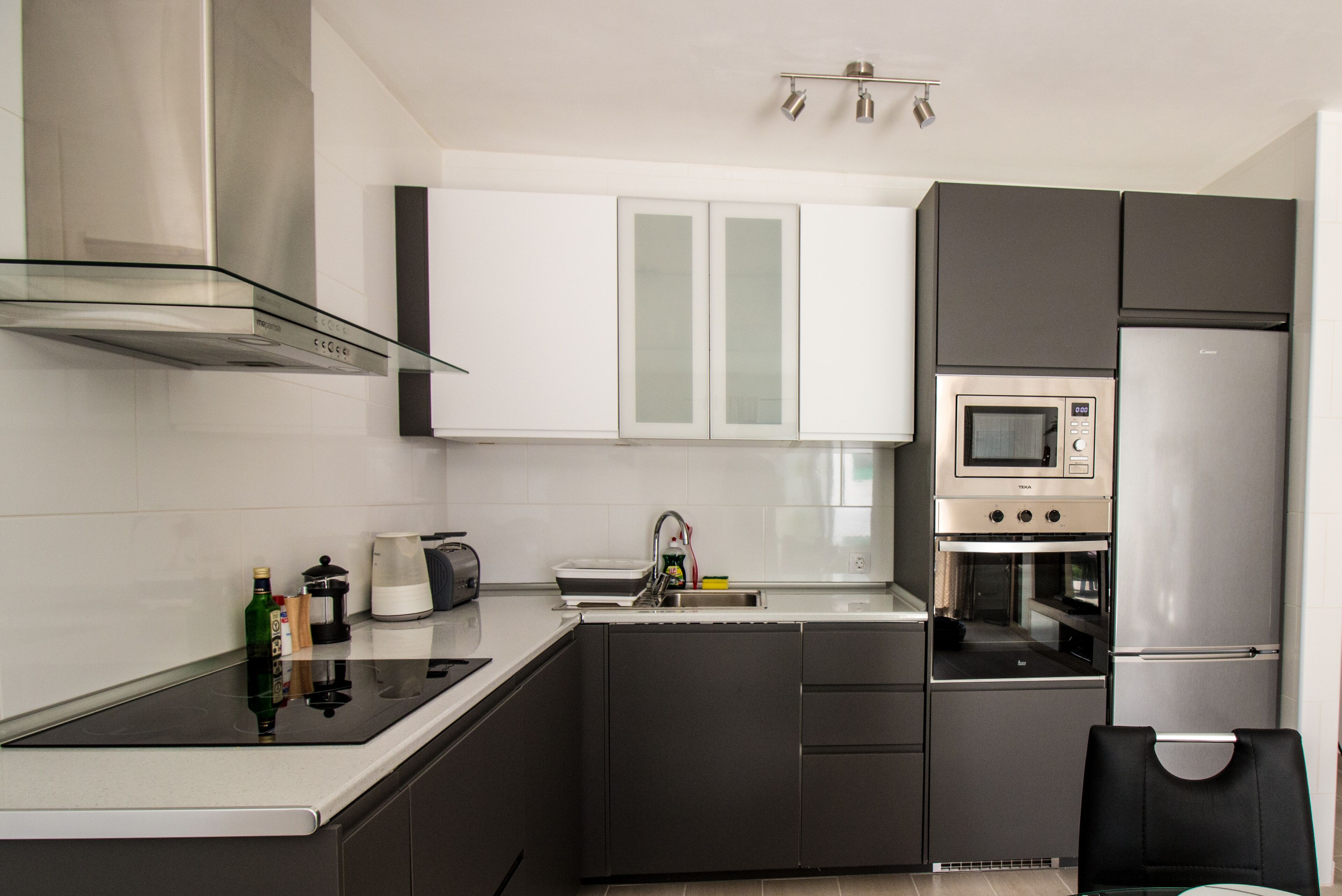 A modern kitchen with a black countertop, stainless steel appliances, and white cabinets.
