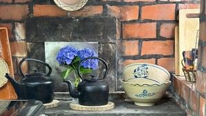Una cocina con pared de ladrillo, dos tetras negros, un florero azul, una cesta tejida y una jarra de cerámica.