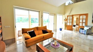 A spacious living room with a large sofa, a coffee table, and a view through large sliding glass doors to the outdoors. - Country house with private pool & Tennis Court  - GREAT for families - Free Wifi (Bunyola)