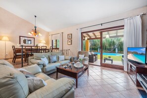 Un salón amplio con sofá, mesa de centro, televisor y comedor con mesa y sillas.