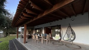 An outdoor patio with a wooden pergola, a table with chairs, and two hanging chairs. - Luxury villa with pool and sea view -Free Wifi (povoa de varzim)