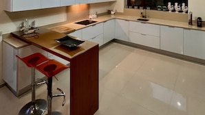 A modern kitchen with a skylight, white cabinets, a wooden countertop, and a bar area with stools. - Luxury villa with pool and sea view -Free Wifi (povoa de varzim)