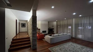 A modern living room with a staircase, a sofa, a TV, and a large window with curtains. - Luxury villa with pool and sea view -Free Wifi (povoa de varzim)