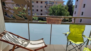 Un balcon avec une chaise pliante en bois, une chaise pliante jaune et un panier tressé.