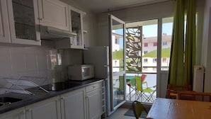 Une cuisine avec des meubles blancs, un four à micro-ondes et un coin repas comprenant une table et des chaises.