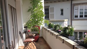 A balcony with a wooden floor, metal chairs, and potted plants. - SUPERB LOFT APARTMENT, CLASS 4*, SOUTH-FACING WITH TERRACE IN THE ORANGERIE DISTRICT (Strasbourg)