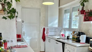 A modern kitchen with a washing machine, a sink, and a dining area with red chairs. - SUPERB LOFT APARTMENT, CLASS 4*, SOUTH-FACING WITH TERRACE IN THE ORANGERIE DISTRICT (Strasbourg)