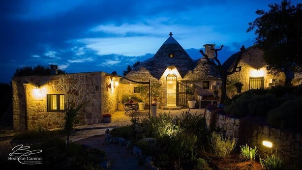 A stone house with a conical roof, a central door, and a small porch area. - Trullo With Private Pool (15x7), WI-FI free, tennis table,mountain bike for rent (Alberobello)