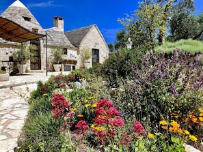 Guests can enjoy a tranquil atmosphere in the beautifully maintained garden surrounded by a variety of flowering plants and shrubs.