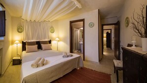 A hotel room with a large bed, two bedside lamps, a mirror, a wooden dresser, and a bathroom visible through an open door. - Trullo With Private Pool (15x7), WI-FI free, tennis table,mountain bike for rent (Alberobello)