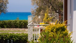 A balcony with a table, yellow flowers, and a view of the sea. - Aeriko-Ammos Beachfront Villa with Stunning View and Private Pool (LEFKADA)