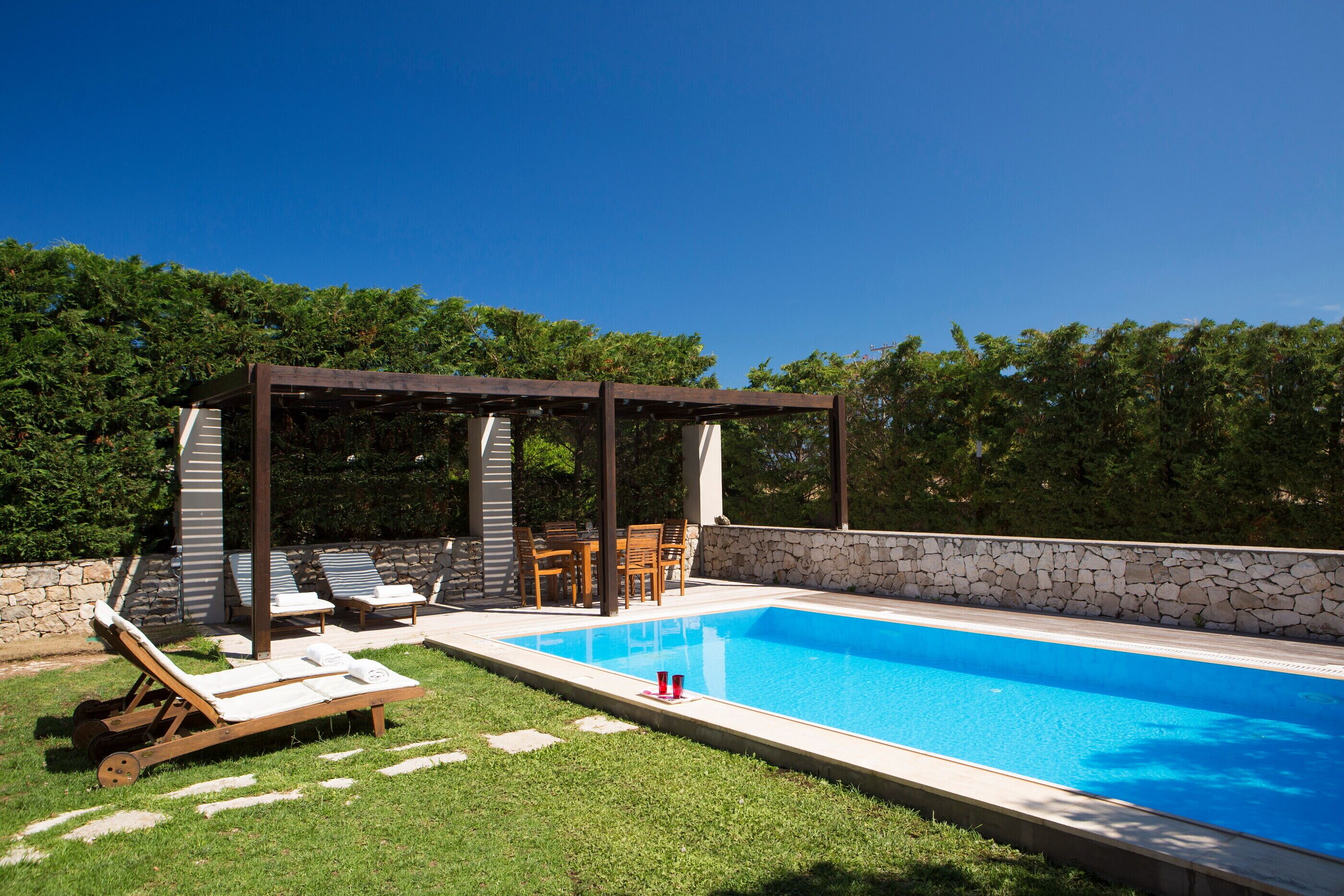 Ein Schwimmbecken mit Liegestühlen und einer Pergola.