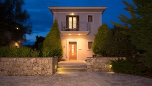 A two-story house with a stone facade, a wooden door, and a balcony with metal railings. - Aeriko-Ammos Beachfront Villa with Stunning View and Private Pool (LEFKADA)