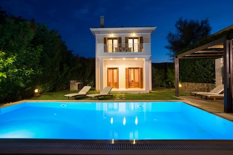 A two-story house with a swimming pool, a covered patio, and a garden.