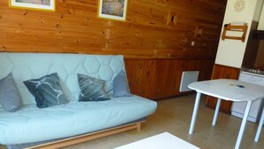 Une pièce avec un canapé bleu clair, une table basse blanche et un plafond en bois.