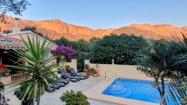 Un espace piscine avec des chaises longues, une petite piscine et une vue sur les montagnes en arrière-plan.