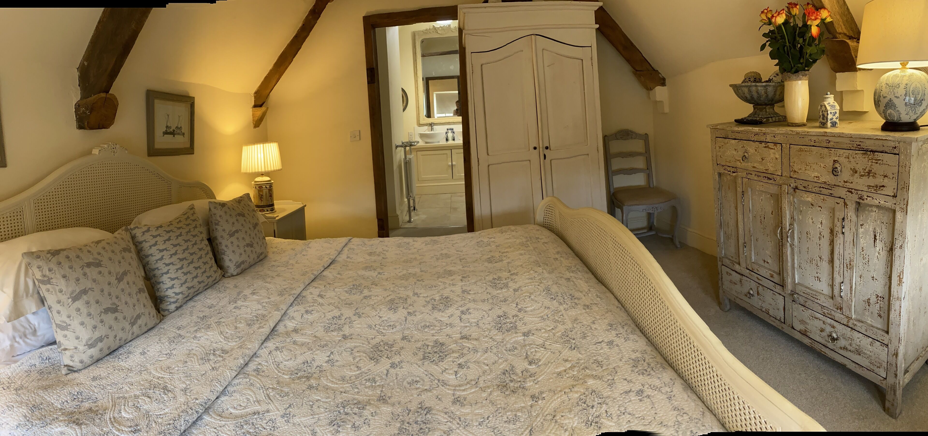 A bedroom with a large bed, a wardrobe, a nightstand, and a mirror.
