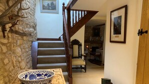 A wooden staircase with a stone wall, a blue and white bowl on a table, and green boots against the wall. - Stunning Interior Designed 2 bedroom House in the center of Chipping Campden (Chipping Campden)