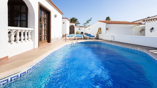A swimming pool with clear blue water, surrounded by white walls and a tiled roof. -  EXCELLENT TWO BEDROOMED  HOLIDAY HOME WITH STUNNING VIEWS AND PRIVATE POOL  (Amarilla Golf)