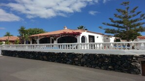 A white building with a red-tiled roof, a stone wall, and a white fence. -  EXCELLENT TWO BEDROOMED  HOLIDAY HOME WITH STUNNING VIEWS AND PRIVATE POOL  (Amarilla Golf)