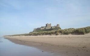 A castle-like structure on a sandy beach with a clear sky. - Seaside House, ideally located on the edge of the coastal village of Seahouses (Seahouses)