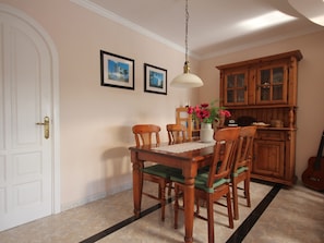 A dining area with a wooden table and chairs, a vase with flowers, and a hanging light fixture. - Beautiful Villa with sea view and heated pool, prime location in Lanzarote. (Puerto Del carmen)